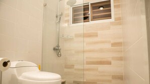 Un baño con inodoro, cabina de ducha y ventana.