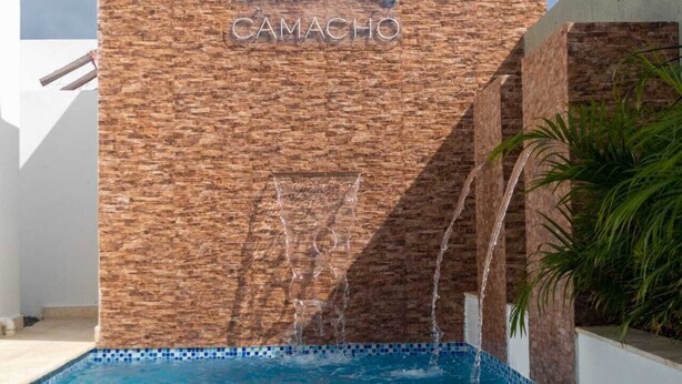 Un muro de ladrillo con la palabra "CAMACHO" y una silueta de caballo.