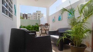 Un espacio al aire libre cubierto con sillas de mimbre y una planta en maceta.