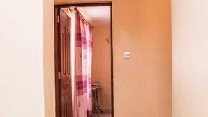 A hallway with a tiled floor, a door with a checkered curtain, and a small table in the background. - Lux Suites Makao Rossyln Apartments (Nairobi)
