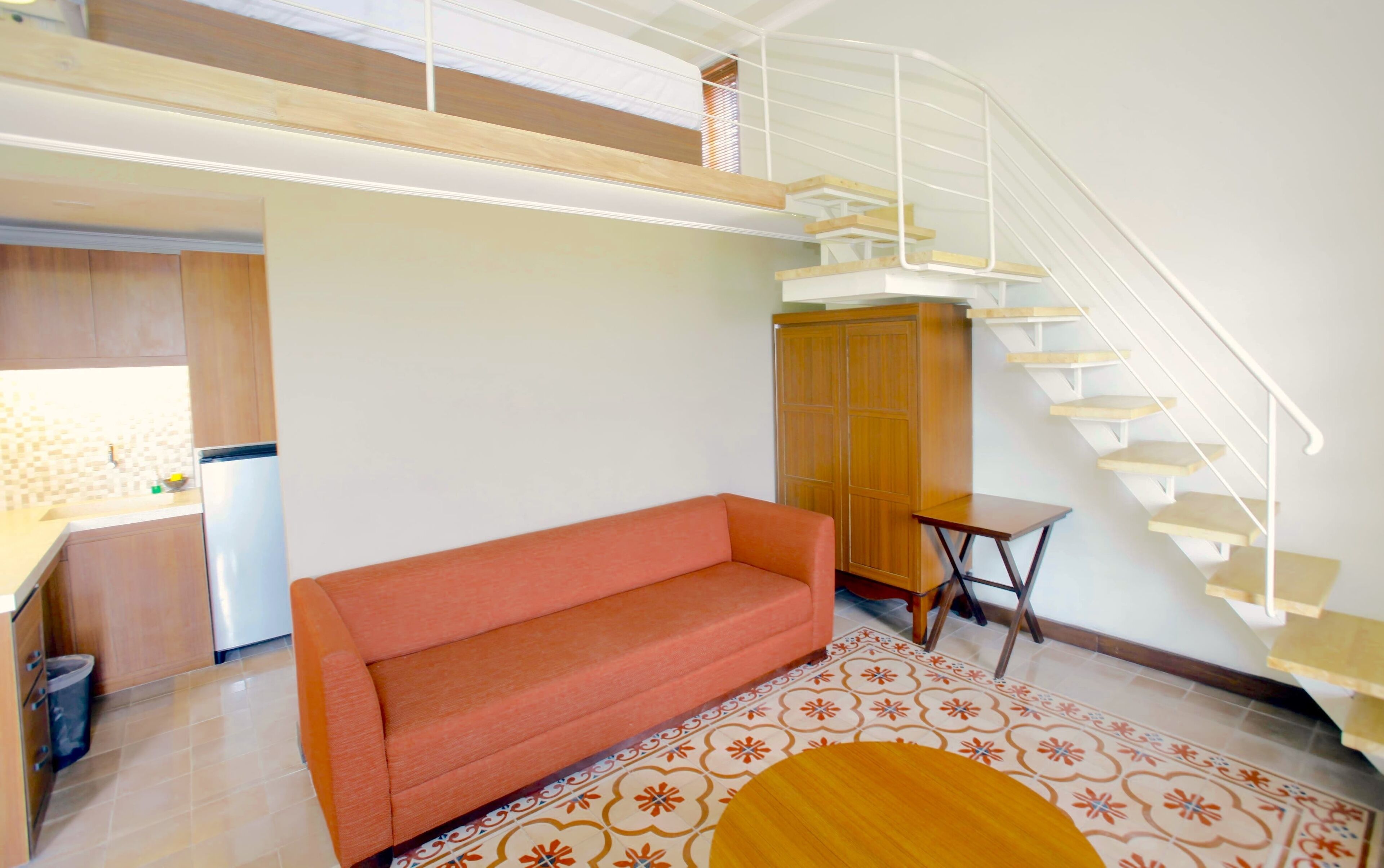A living room with a sofa, a small table, a cabinet, and a staircase.