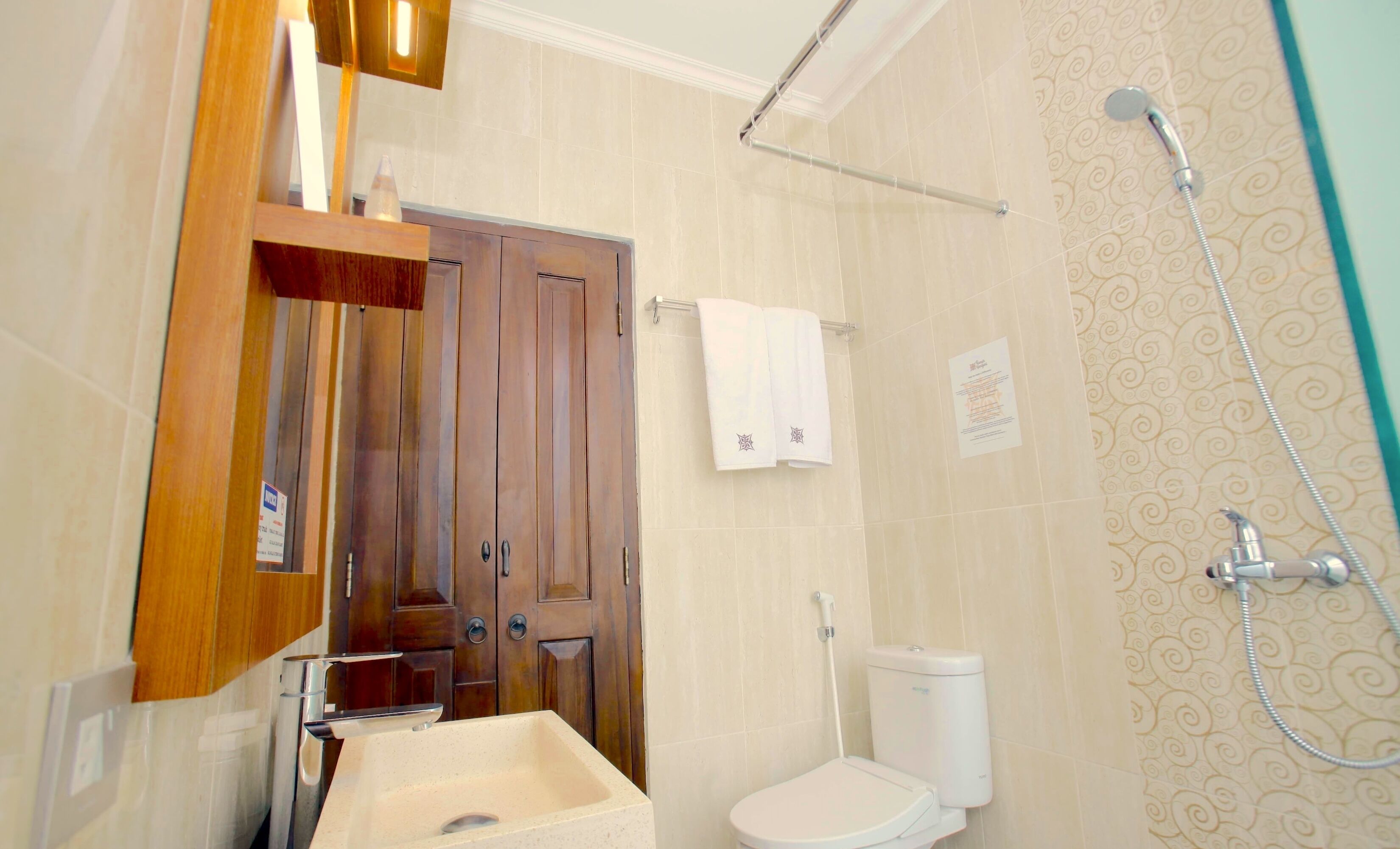 Un baño con puerta de madera, un lavamanos, un inodoro y una ducha.