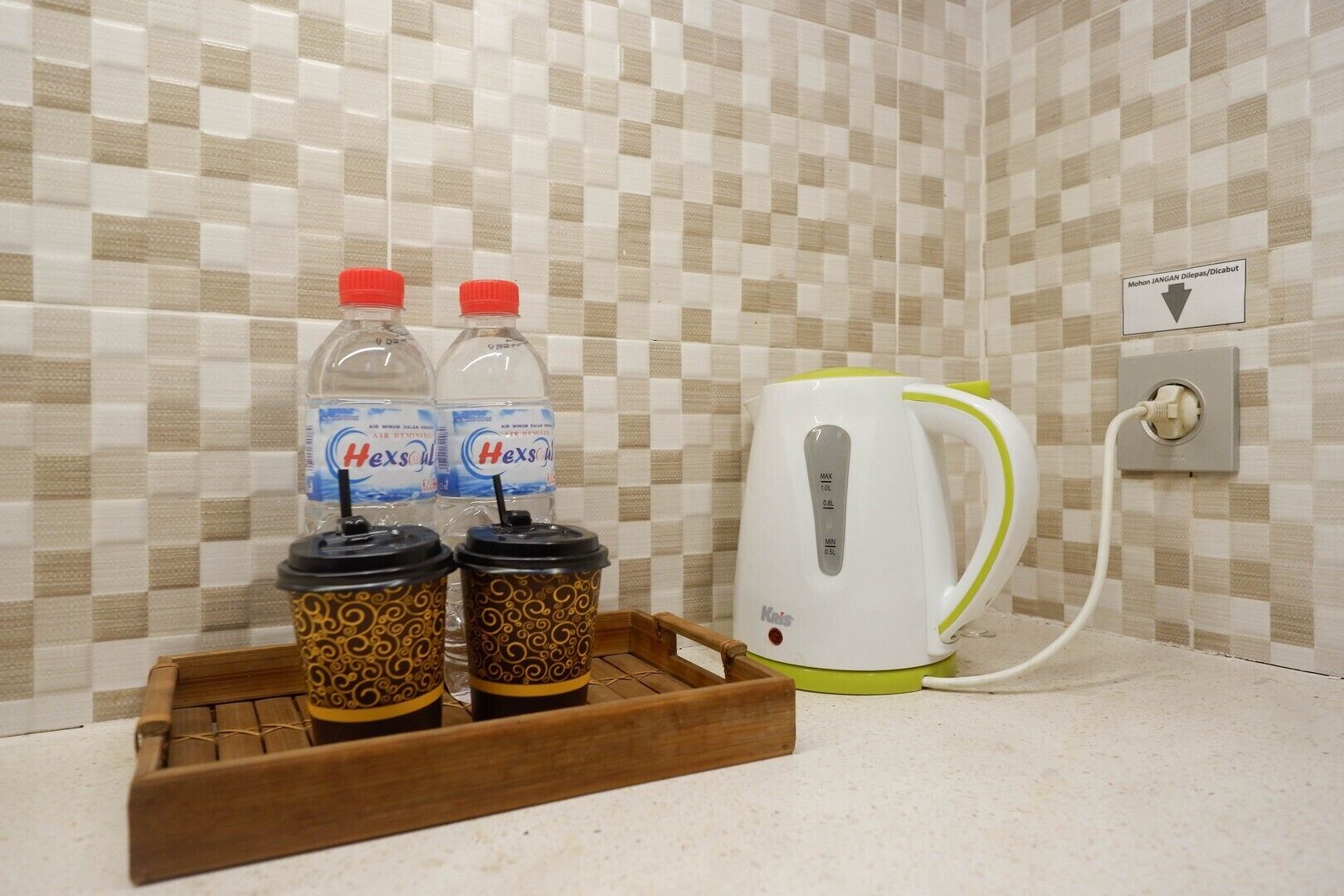 A kitchenette area with a coffee maker, two water bottles, and a tray with two coffee cups.