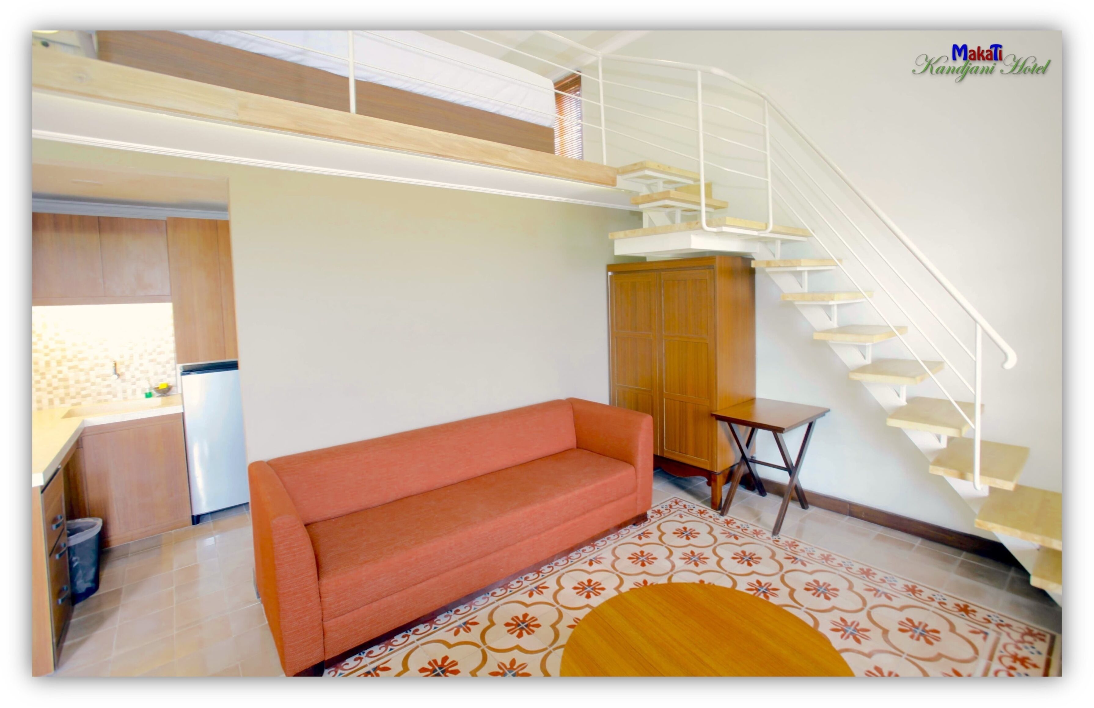 Una habitación de hotel moderna con sofá, una mesita, una escalera y una zona de cocina.