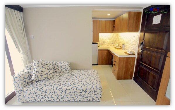 A compact living space with a sofa, kitchenette, and a wooden door.