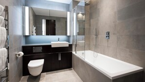 A modern bathroom with a glass-enclosed shower, a white bathtub, and a dark vanity with a mirror. - Luxury Riverfront Retreat in London (London)
