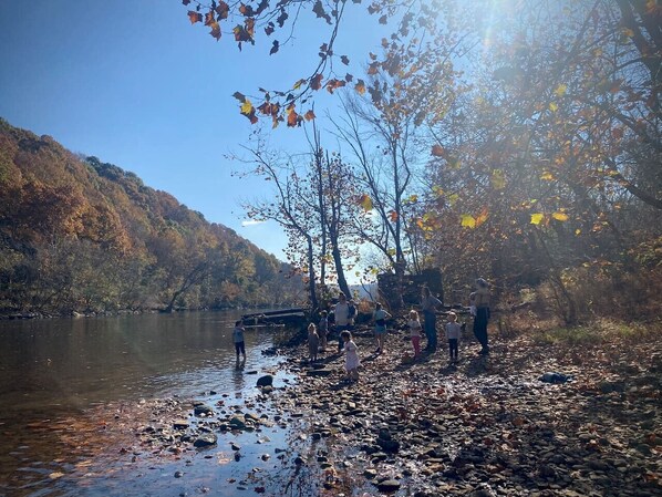 A group of people by a river with a bridge in the background.