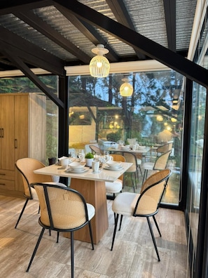 A dining area with a large table, chairs, and pendant lighting.