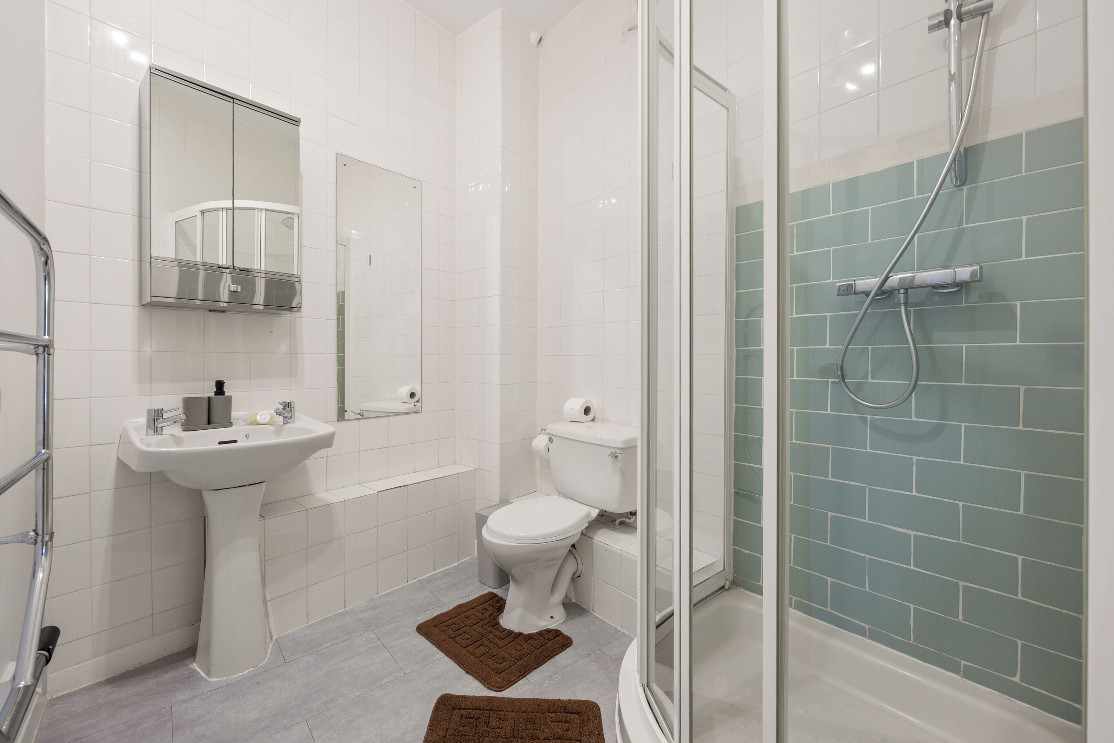 Een moderne badkamer met een wit wastafelmeubel, toilet en douchegedeelte.