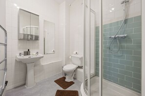 A modern bathroom with a white sink, toilet, and shower area. - Prime Soho 2BR/2BA Apartment with A/C (London)