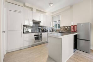 A modern kitchen with white cabinetry, stainless steel appliances, and a central island.