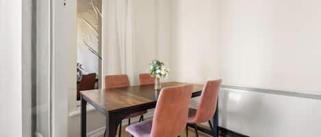 A dining area with a wooden table, four chairs, and a vase with flowers.
