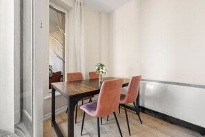 A dining area with a wooden table, four chairs, and a vase with flowers. - Prime Soho 2BR/2BA Apartment with A/C (London)