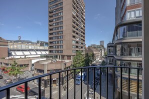 A high-rise building with multiple floors, a street view with parked cars, and a clear sky.