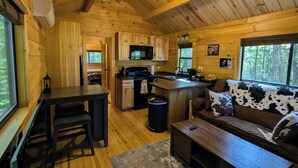 Ein gemütliches Blockhaus-Interieur mit Küche, Essbereich und Wohnzimmer mit einer Couch.