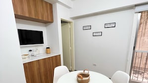 A modern kitchen with a TV, wooden cabinets, and a dining area with a round table and white chairs.