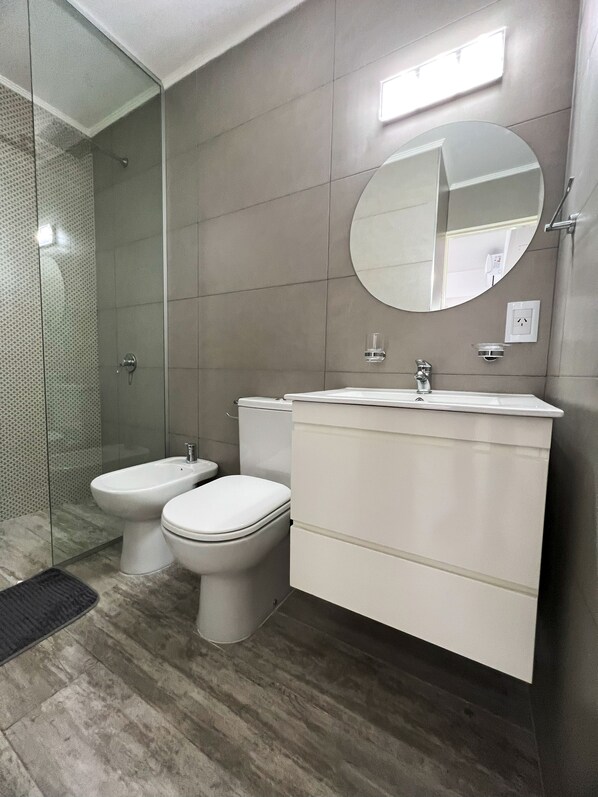 A modern bathroom with a glass shower enclosure, a bidet, a toilet, and a vanity with a mirror. - RentUp- Monoamb. zona Recoleta Urbana (Buenos Aires)