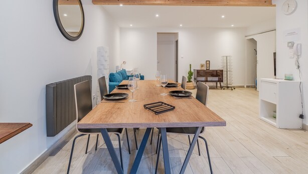 Een moderne eetruimte met een houten tafel, zwarte stoelen en een wit plafond.