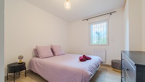 Een slaapkamer met een bed, nachtkastje, kledingkast en een raam met uitzicht.