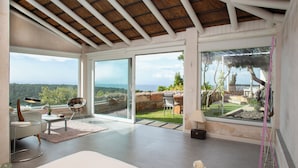 A spacious room with large sliding glass doors leading to a garden, a white sofa, a small table, and a dog. - Love Garden (Tarifa)