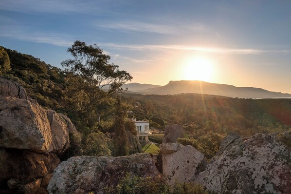 Una casa rodeada de terreno rocoso y árboles, con una vista despejada del paisaje.