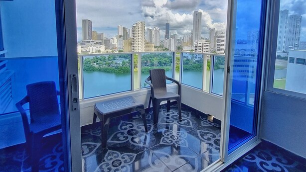 Ein Balkon mit Blick auf die Stadt, mit gemusterten Bodenfliesen und einem Stuhl.