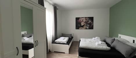 A bedroom with two beds, a wardrobe, and a painting on the wall.