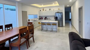 Una cocina moderna con una isla central, un comedor con sillas de madera y una sala de estar con sofá.