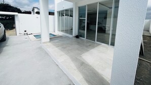 Una casa moderna con porche cubierto, grandes puertas correderas de vidrio y piscina.