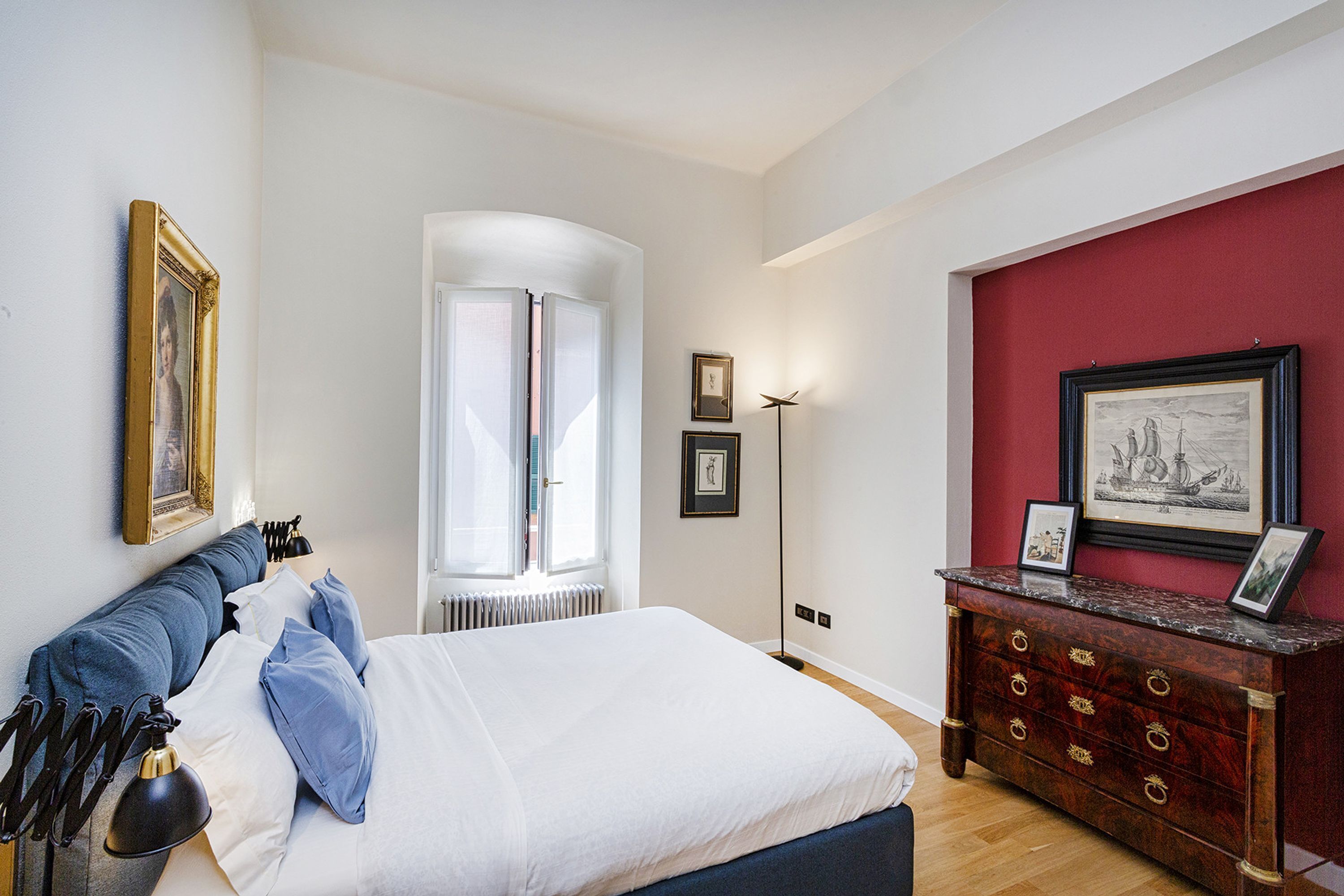 Une chambre à coucher avec un lit, une table de chevet, une commode et des tableaux encadrés accrochés au mur.