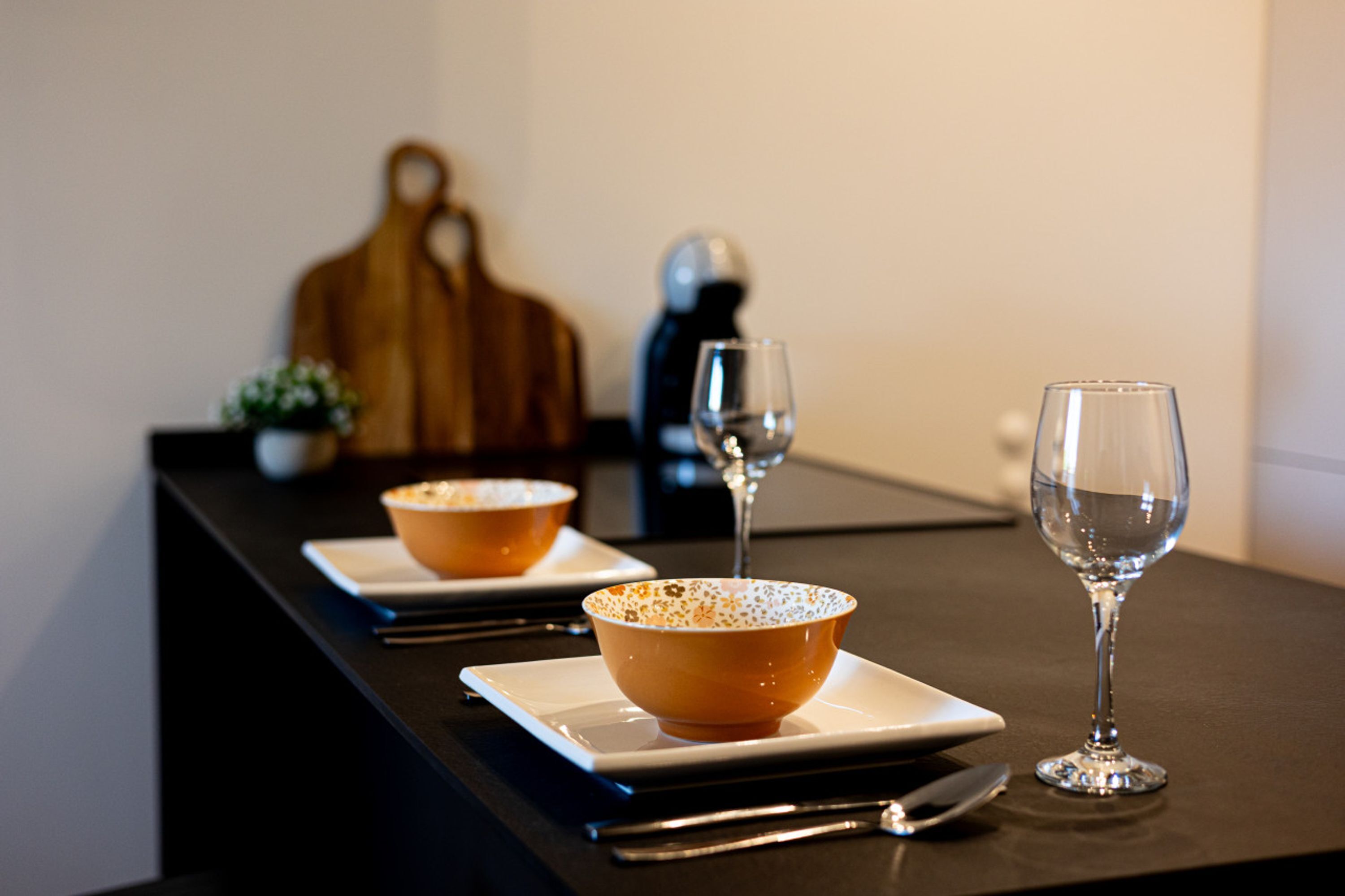A dining table with two bowls and two wine glasses.