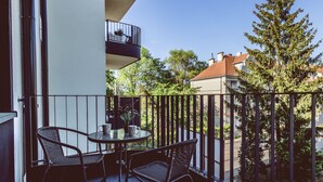 A balcony with two wicker chairs and a small round table, overlooking a residential area with trees and houses. - Pueblo Spacerkiem Brd na Stary Rynek Gara (Bydgoszcz)