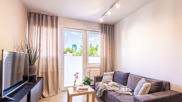 A modern living room with a flat-screen TV, a sofa, a coffee table, and a large window with curtains. - Pueblo Spacerkiem Brd na Stary Rynek Gara (Bydgoszcz)