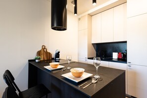 Een moderne keuken met een centraal eiland, witte kasten en een zwart aanrecht.