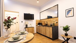 Une cuisine moderne avec des meubles en bois, un plan de travail en marbre noir et un grand miroir. On y trouve une table à manger avec de l’assiette, des couverts et un vase rempli de fleurs.