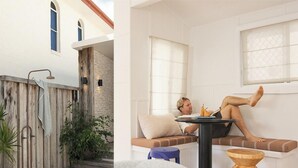 A room with a wooden bench, a small table, and a window with blinds. - Bay Properties . Our Place (Yamba)
