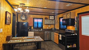 Una cocina con paredes de madera, una mesa de comedor con individuales, un refrigerador, un microondas y un lavabo.