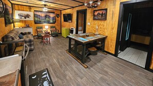 Una habitación acogedora con paredes de madera, un sofá, una mesa con obras de arte y una televisión.