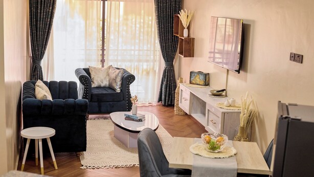 Ein modernes Wohnzimmer mit einem dunklen Sofa, einem runden Couchtisch und einem Essbereich mit einem hellen Tisch.