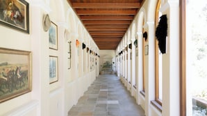 A corridor with a tiled floor, white walls, and wooden ceiling beams. - Manor House at La Roche Estate - Franschhoek (Franschhoek)