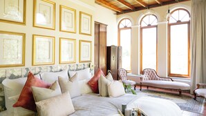 A spacious bedroom with a large bed, multiple pillows, a bedside table with candles, and a view through arched windows. - Manor House at La Roche Estate - Franschhoek (Franschhoek)