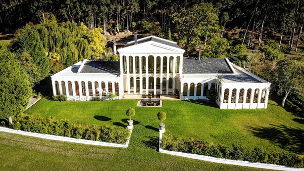 A large, white, classical-style building with a symmetrical facade, central entrance, and a well-maintained lawn with trimmed hedges. - Manor House at La Roche Estate - Franschhoek (Franschhoek)