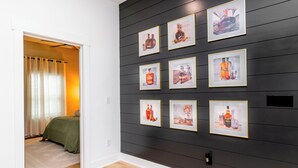 Una habitación con una pared de madera oscura con obras de arte enmarcadas, una cama con ropa de cama verde y una alfombra de color claro.