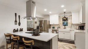 A modern kitchen with a large island, white cabinetry, and a herringbone tile backsplash.