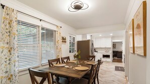 A dining area with a wooden table set for six, surrounded by wooden chairs.