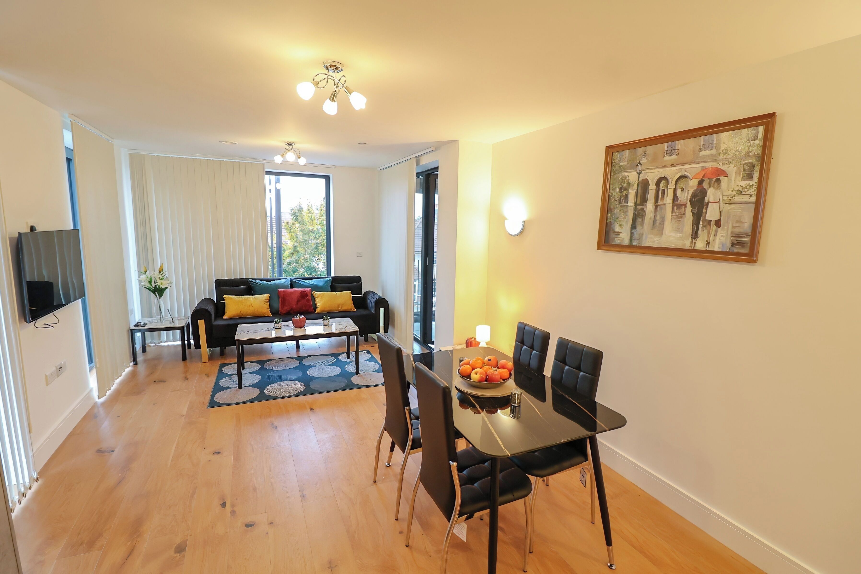 A modern living room with a dining area, featuring a sofa, coffee table, and a painting on the wall.