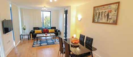 Ein modernes Wohnzimmer mit Essbereich, inklusive Sofa, Couchtisch und einem Gemälde an der Wand.