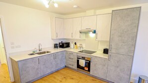 A modern kitchen with grey cabinets, a stainless steel sink, and a built-in oven.