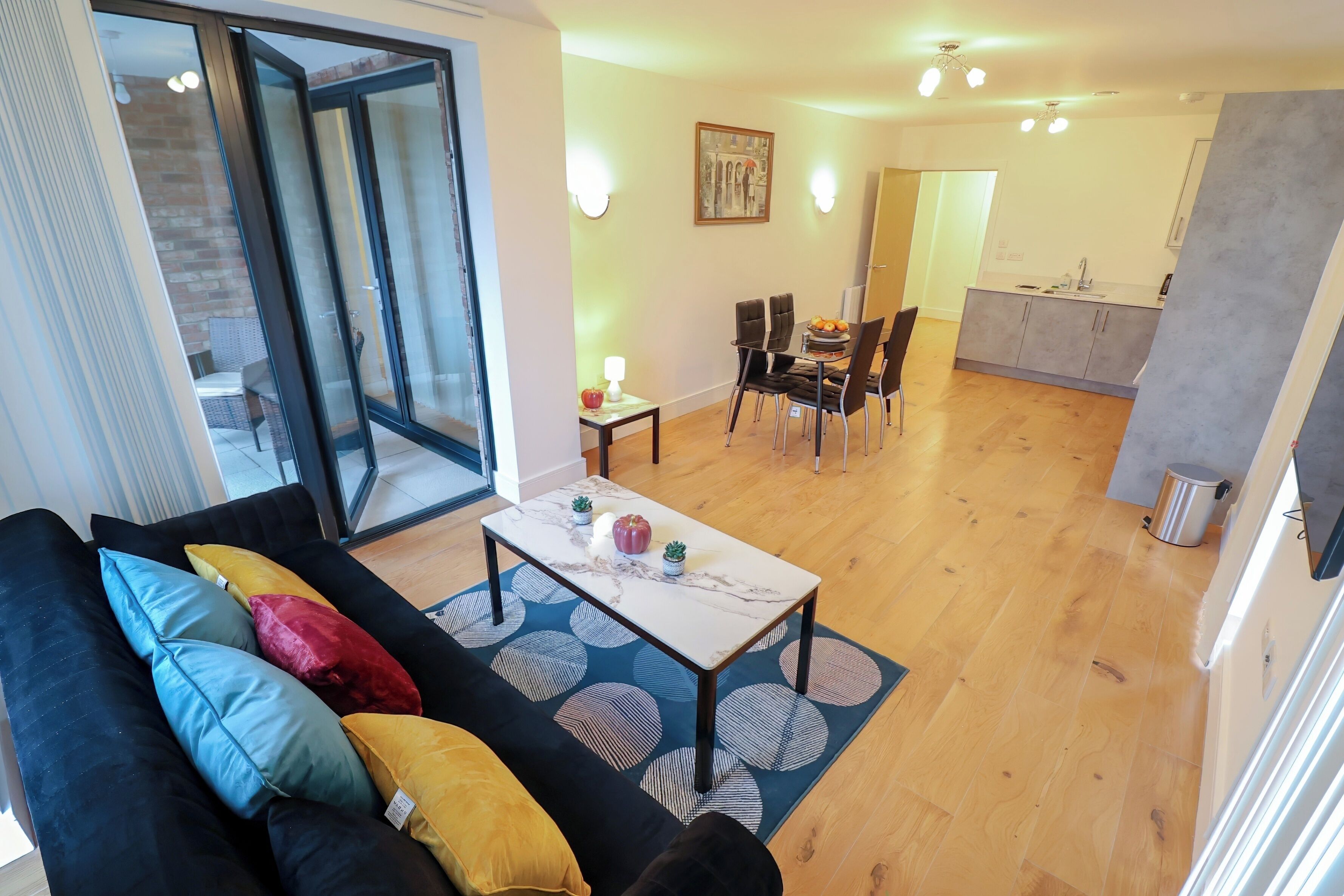 Ein modernes Wohnzimmer mit einer schwarzen Couch, einem Couchtisch und einem Essbereich mit Stühlen und einem Tisch.