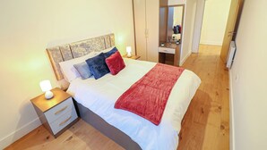 A bedroom with a bed, nightstand, wardrobe, and a mirror.